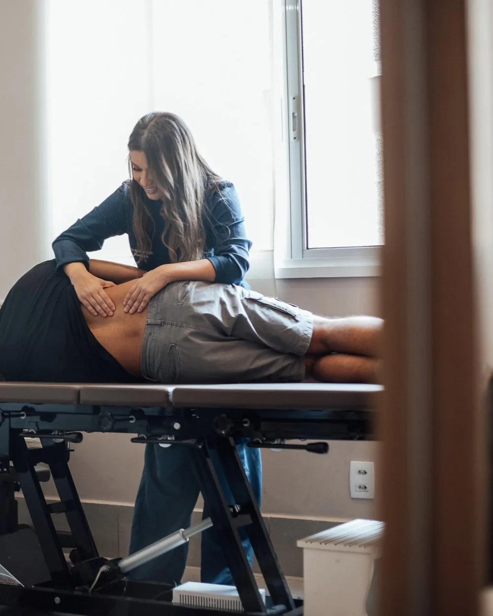 Karollyne Bomfim realizando terapia manual na região lombar de um paciente